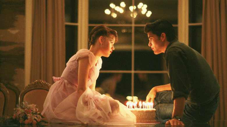 Sam (Molly Ringwald) and Jake (Michael Schoeffling) lean into kiss over a birthday cake in Sixteen Candles