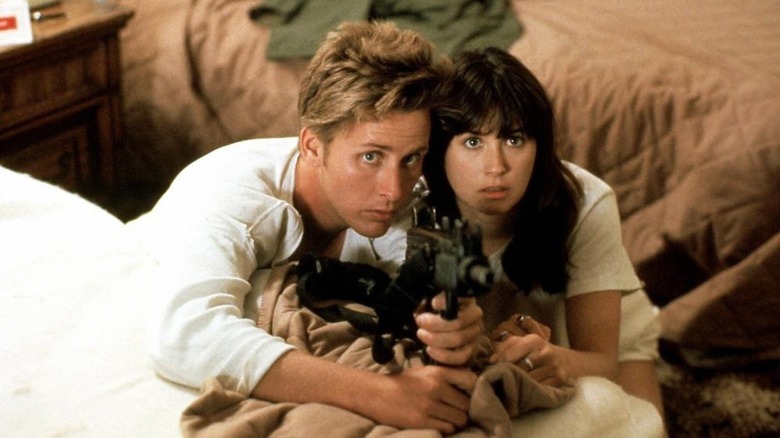 Wisdom (Emilio Estevez) and Karen (Demi Moore) hold a submachine gun together in Wisdom