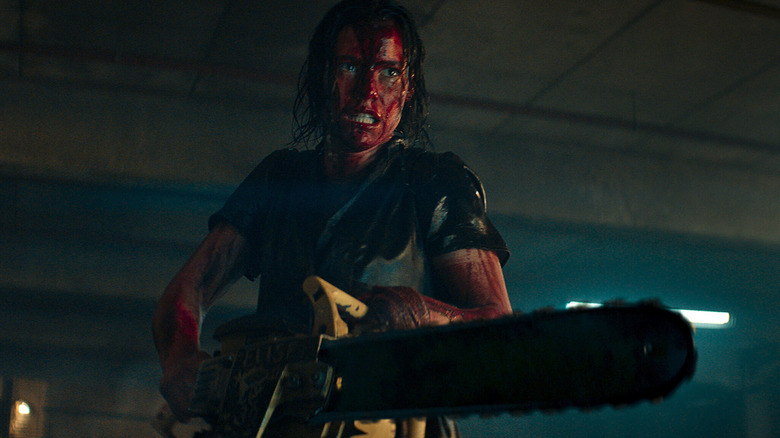 Beth, covered in blood and holding a chainsaw, grimaces in Evil Dead Rise.