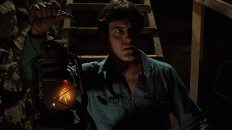 Ask, holding a lantern, venturing into a basement in The Evil Dead.