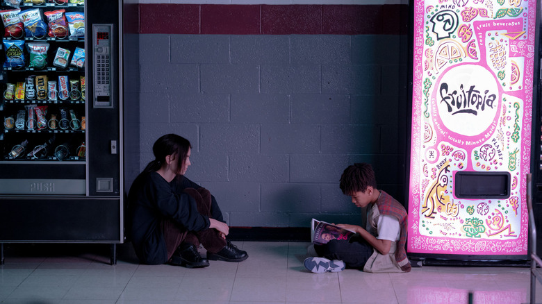 Owen sitting on the cafeteria floor with Maddy between the vending machines in I Saw the TV Glow