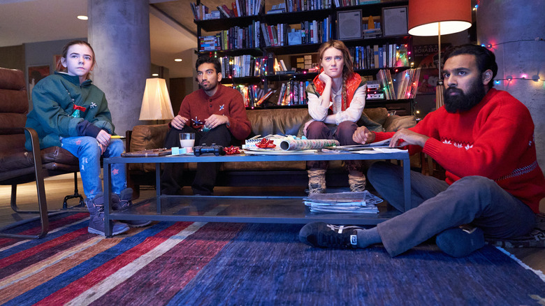 Matilda Lawler as young Kirsten, Nabhaan Rizwan as Frank, Mackenzie Davis as Kirsten, and Himesh Patel as Jeevan sitting at a table in Station Eleven