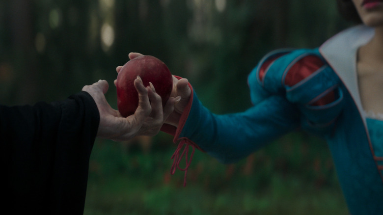 Gal Gadot's Evil Queen handing the poisoned apple to Rachel Zegler's Snow White in Disney's Snow White remake