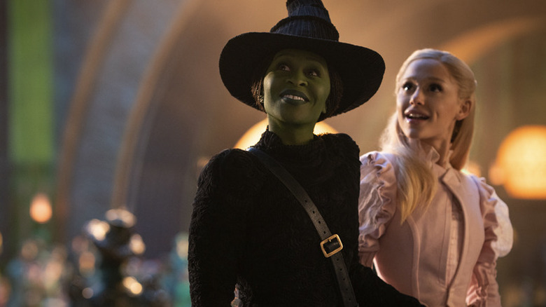 Elphaba and Glinda in Emerald City looking up and smiling at something offscreen in Wicked