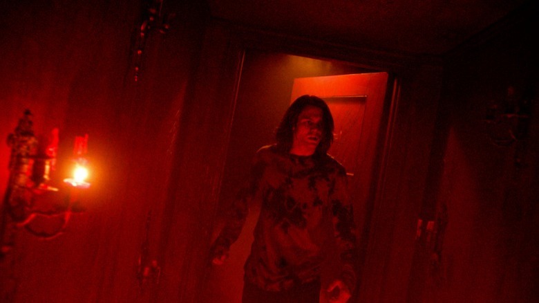 Dalton walks through a door bathed in red light