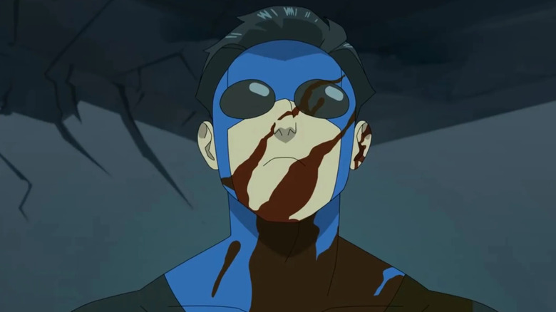 Invincible in the blue suit with his face covered in blood