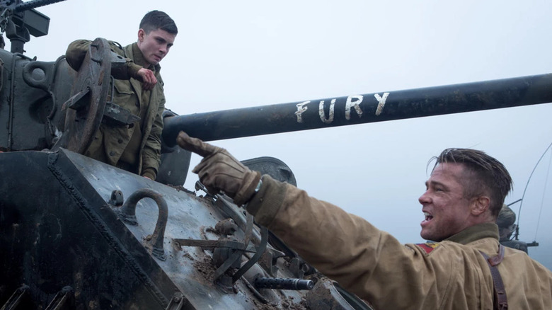 Norman sits on top of a military tank labeled Fury while Don angrily points his leather-gloved hands to the left in Fury