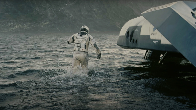 An astronaut hurrires towards a ship on a water planet in Interstellar