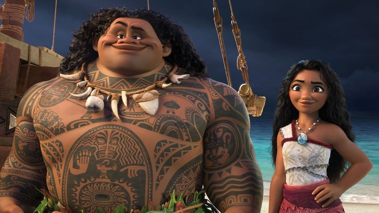 Maui ad Moana standing next to each other on the shore of a beach in Moana 2