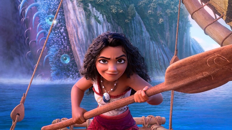 Moana standing on her boat, holding an oar pointed forward in Moana 2