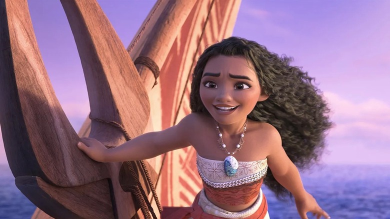 Moana of Motonui leaning forward on her boat sailing on the ocean, smiling and looking to the horizon, in Moana 2