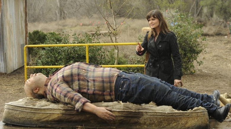 Emily Deschanel as Dr. Brennan looking at a corpse on Bones