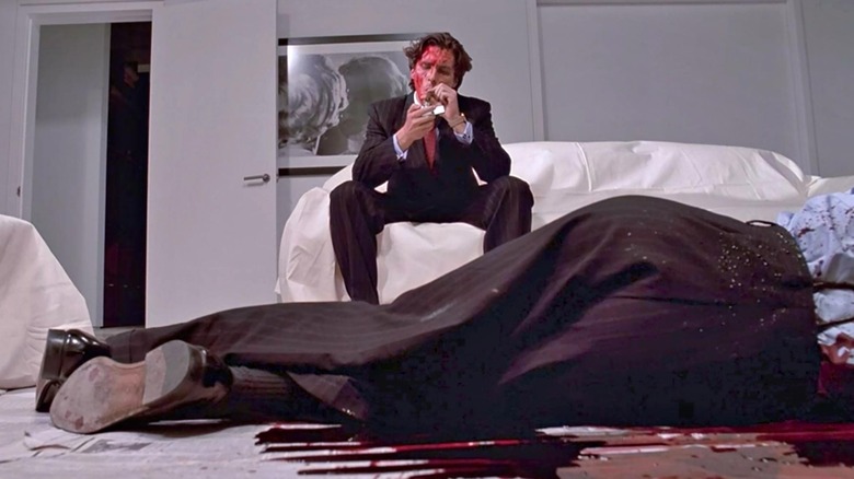 Patrick Bateman in American Psycho lights a cigarette over a dead body