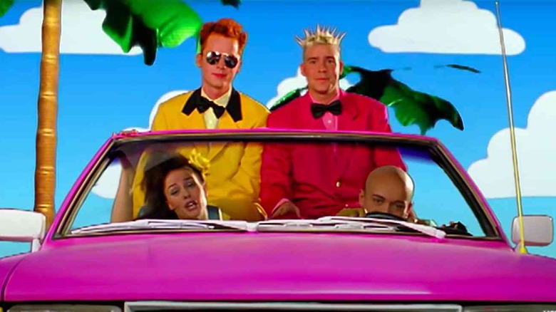 aqua band members in a cartoon car and bright suits in the barbie girl music video