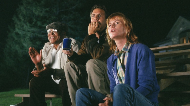 Ray, Terence, and Annie watching a baseball game from the bleachers in Field of Dreams