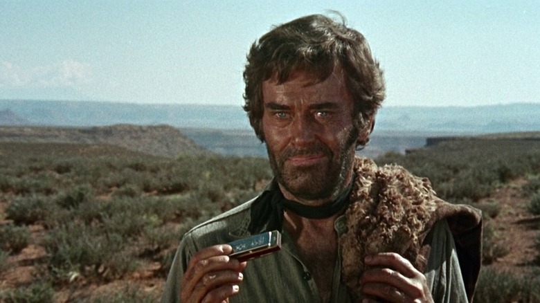 Frank from 'Once Upon a Time in the West,' holding a harmonica and smirking in an evil fashion