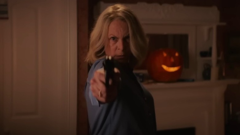 Halloween End's Laurie points pistol at screen