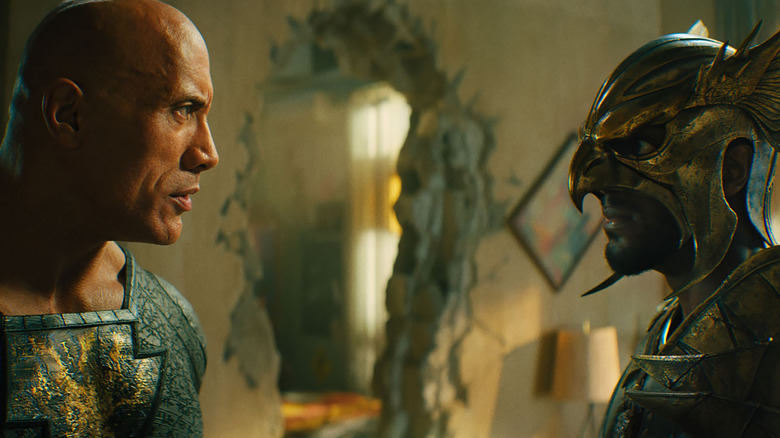 dwayne johnson as black adam standing across from a man in an eagle-style gold helmet in the movie black adam