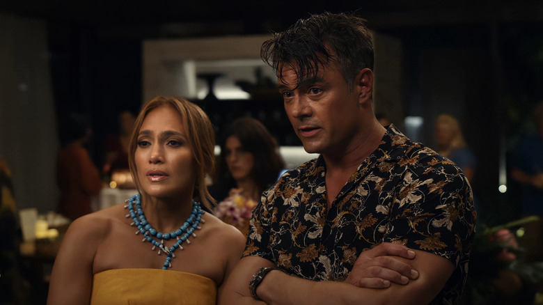 Jennifer Lopez's Darcy Rivera and Josh Duhamel's Tom Fowler stand side by side as they look across a party in Shotgun Wedding