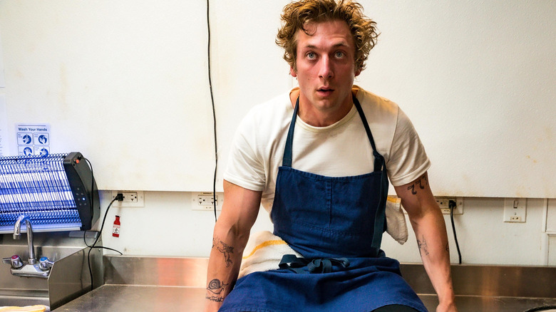 Jeremy Alan White as Carmy sitting on the counter in the kitchen in The Bear