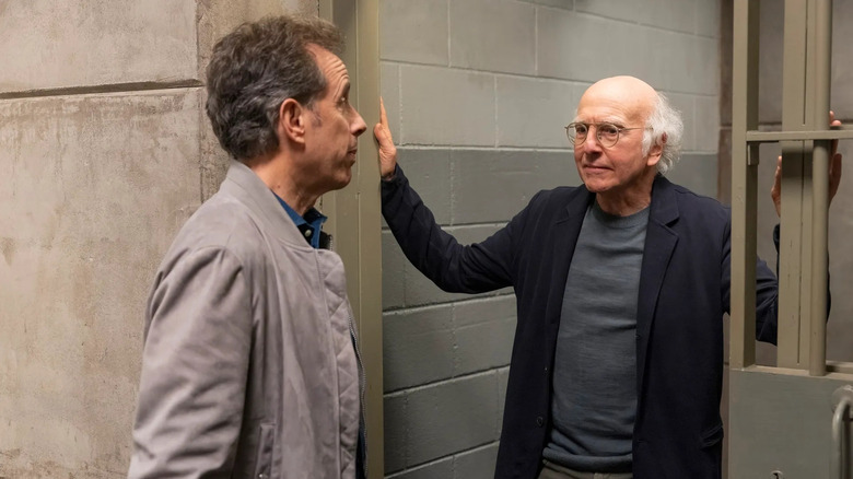 Jerry Seinfeld and Larry David stand at the threshold of a jail cell in Curb Your Enthusiasm