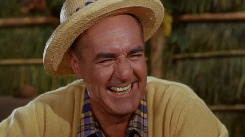 Jim Backus 'Thurston Howell III tersenyum sambil mengenakan topi di Pulau Gilligan