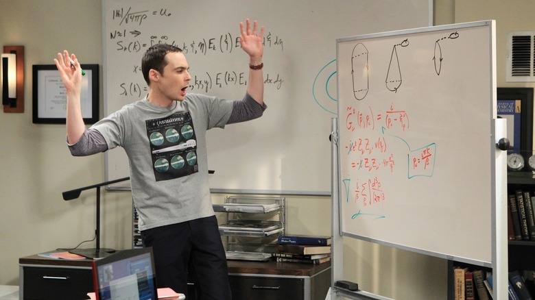 Sheldon exclamando perto de um quadro branco sobre The Big Bang Theory