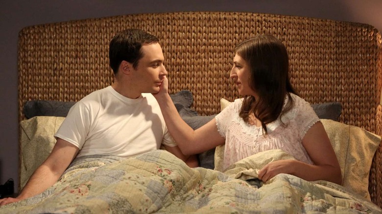 Amy putting her hand on Sheldon's face in their bed The Big Bang Theory