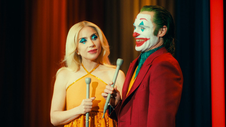 Joaquin Phoenix grins as Arthur Fleck alongside Lady Gaga as Lee Quinzel in Joker Folie a Deux