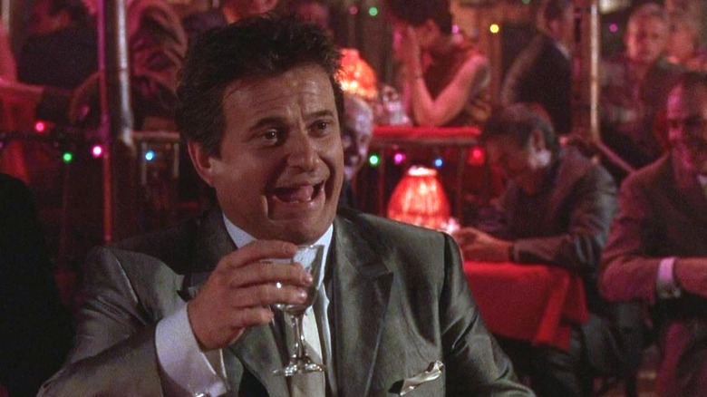 Joe Pesci's Tommy DeVito laughing and holding a glass in Goodfellas