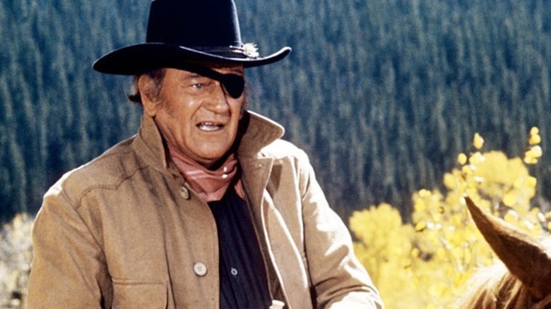 John Wayne cavalga no alto da sela como galo Cogburn em True Grit