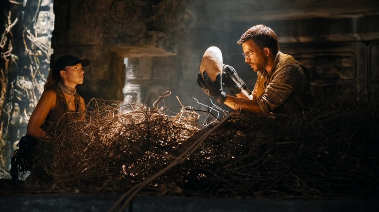 Scarlett Johansson as Zora Bennett and Jonathan Bailey as Dr. Henry Loomis inspecting a dinosaur egg in Jurassic World Rebirth