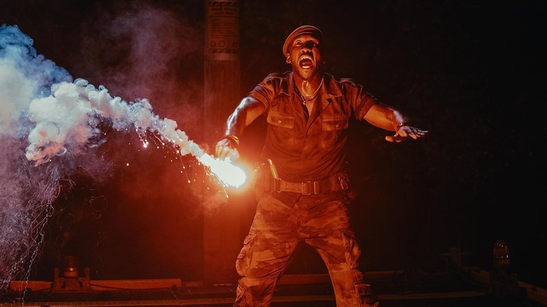 Mahershala Ali as Duncan Kincaid yelling while holding a red flare in Jurassic World Rebirth