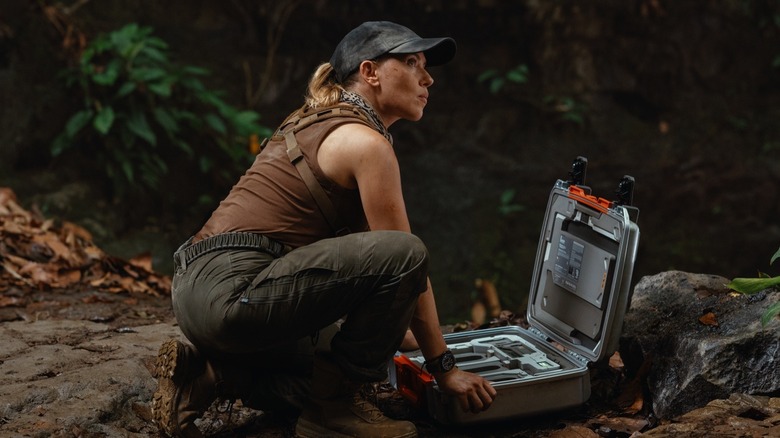 Scarlett Johansson as Zora Bennett crouched over a briefcase in Jurassic World Rebirth