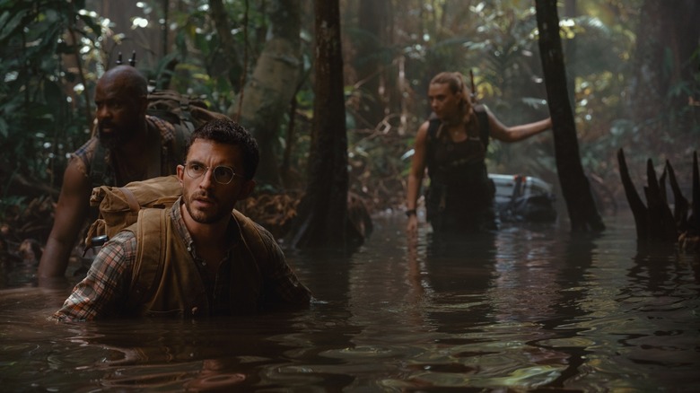 Scarlett Johansson as Zora Bennett, Jonathan Bailey as Henry Loomis, and Bechir Sylvain wading through the water in Jurassic World Rebirth