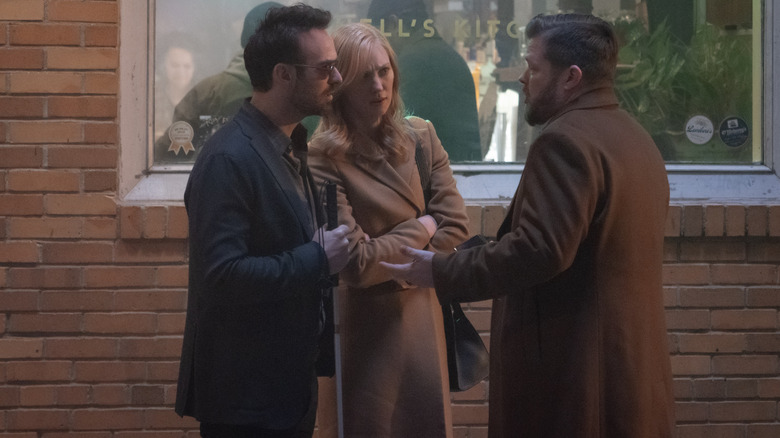 Charlie Cox as Matt Murdock, Deborah Ann Woll as Karen Page, and Elden Henson as Foggy Nelson talking animatedly on a sidewalk in Daredevil: Born Again