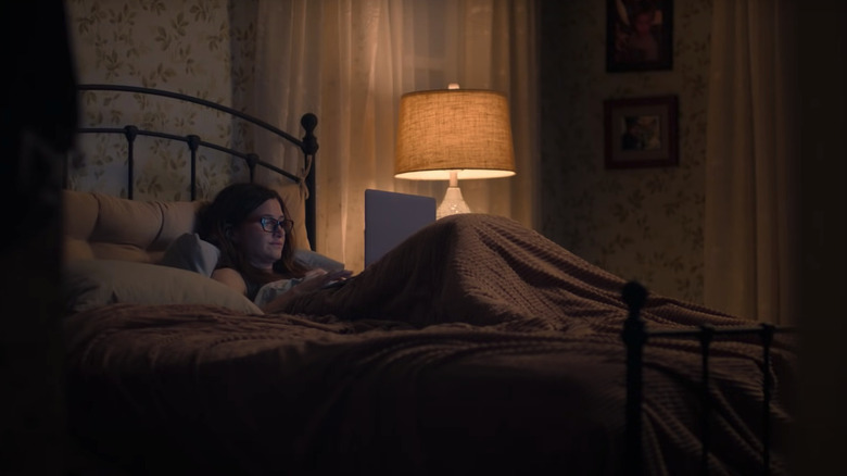 Kathryn Hahn as Eve Fletcher lying in bed looking at her laptop in Mrs. Fletcher