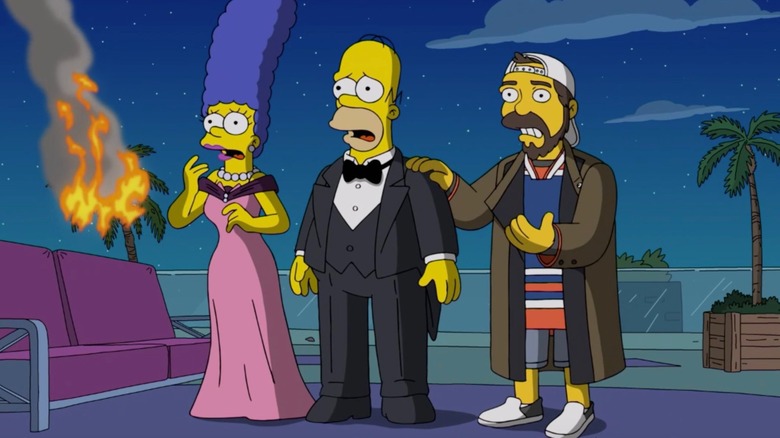 Homer and Marge Simpson in fancy evening wear, staring aghast at something offscreen. A palm tree is on fire. Kevin Smith stands next to them.