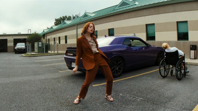 Emma Stone as Emily dancing in front of her car in Kinds of Kindness