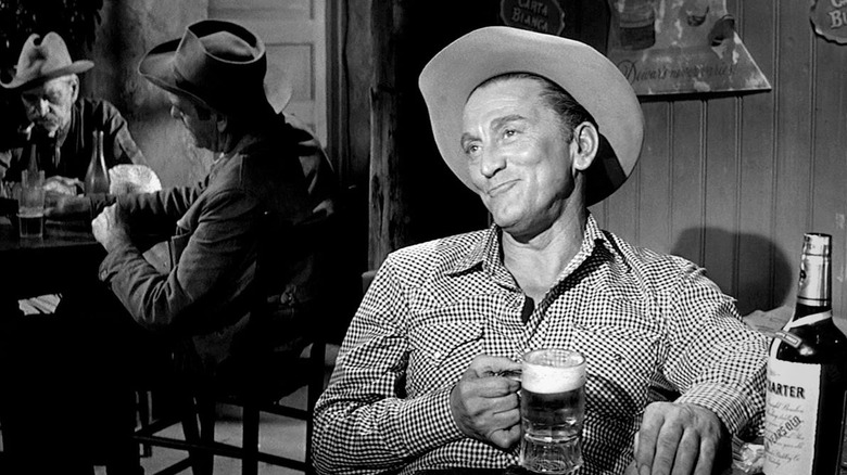 Jack Burns from Lonely Are the Brave, sitting in a bar, enjoying a beer and smirking