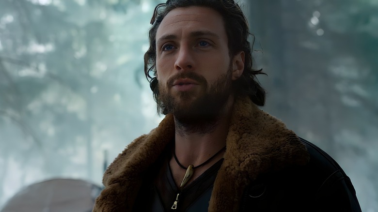 Aaron Taylor-Johnson as Kraven standing in the forest in Kraven the Hunter