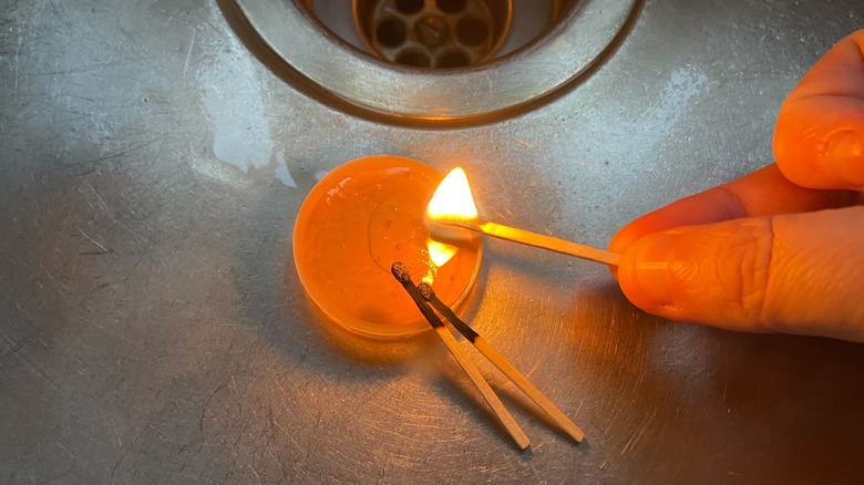 A plastic milk top filled with honey being tested by flame