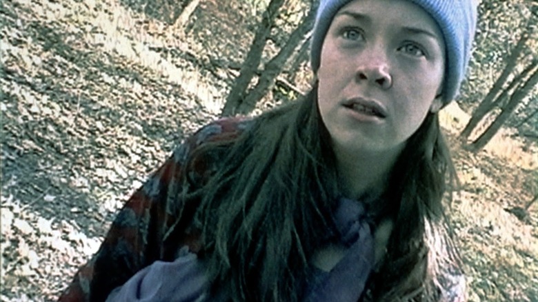 woman in blue cap standing in the woods