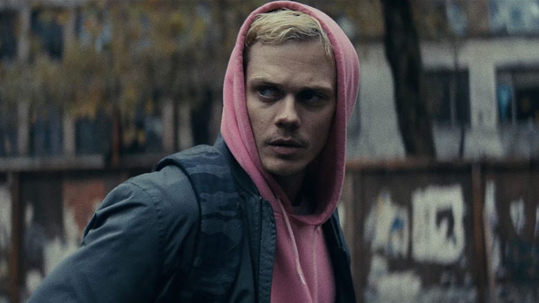 Eddie de Bill Skarsgard in a pink hoodie standing in the streets