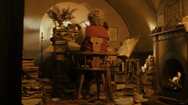 Bilbo sitting at his desk in his cluttered study