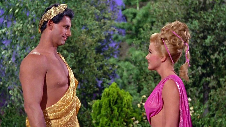 Michael Forest's Apollo, wearing a shiny golden toga, stands opposite Leslie Parrish's Caroline, who wears a hot pink toga, in Star Trek: The Original Series