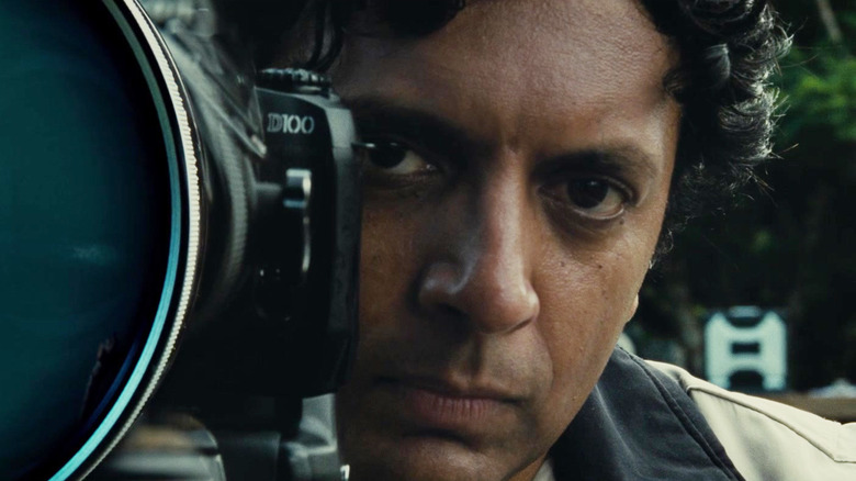 M. Night Shyamalan as a resort employee watches from behind a camera in Old