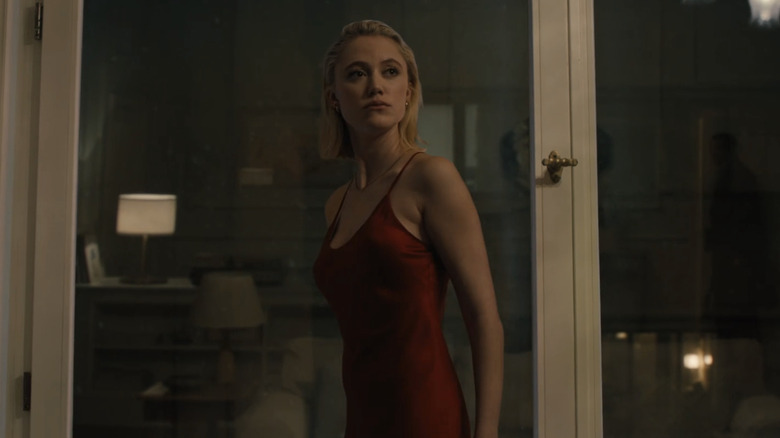 Julia de Maika Monroe fica ao lado de uma janela no observador