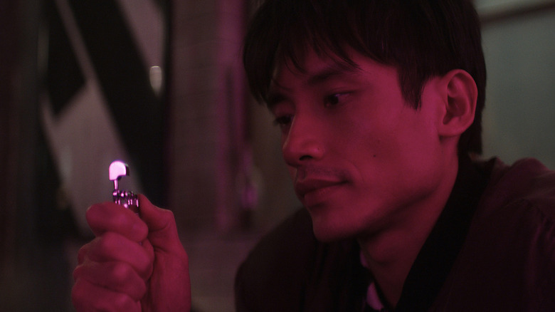 Manny Jacinto as Code holding a silver object in Brand New Cherry Flavor