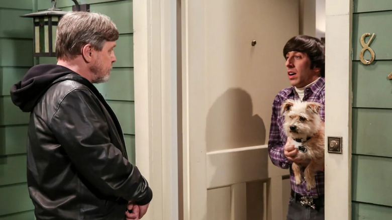 Mark Hamill and Howard hold a dog and talk in a hallway in The Big Bang Theory